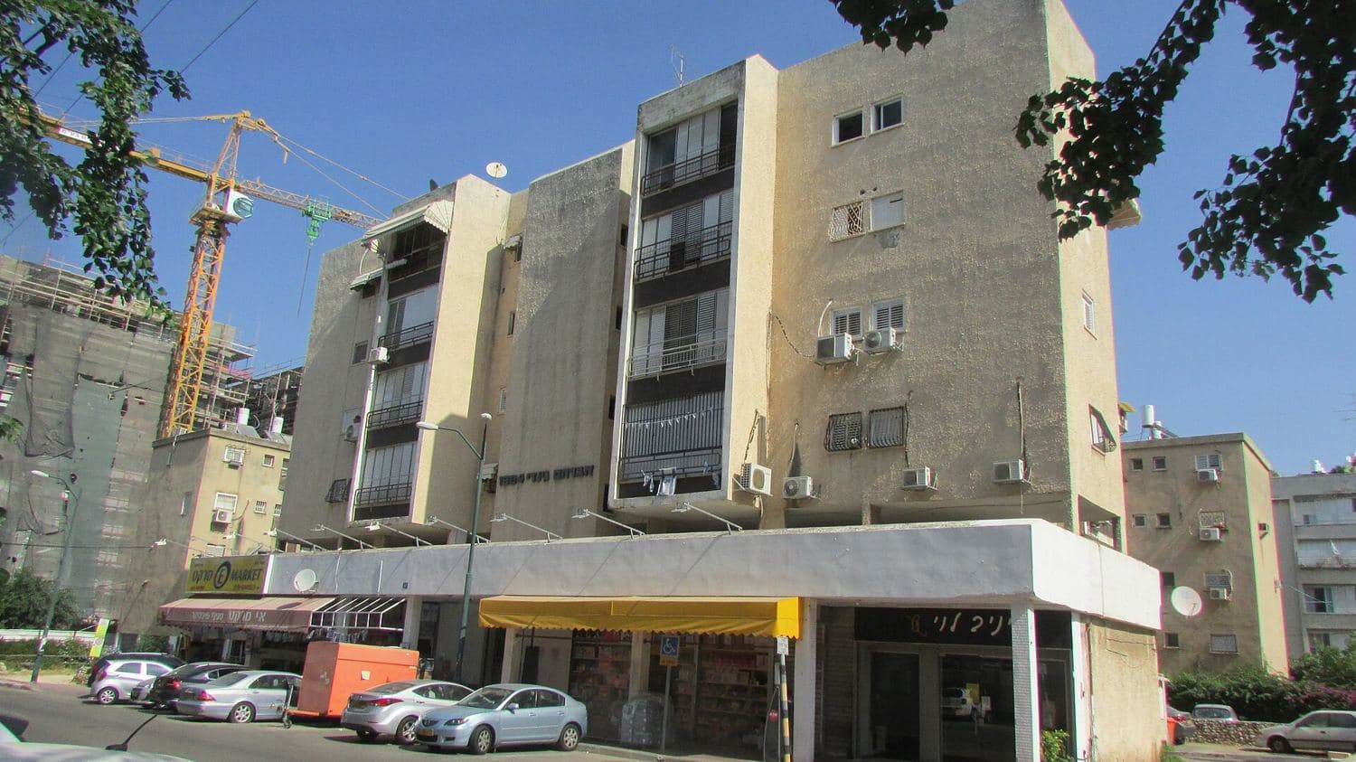 בניין מגורים ישן עם מנוף בנייה ברקע